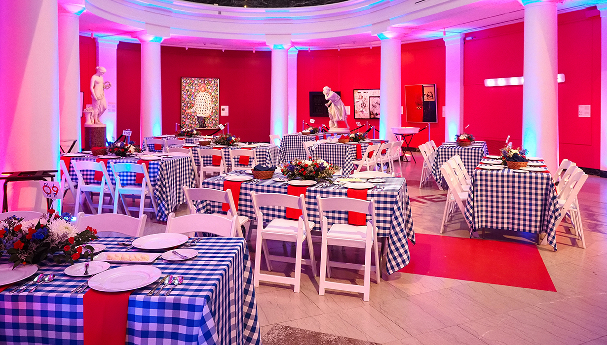 Tables and chairs set up in an art museum gallery in preparation for a dinner event