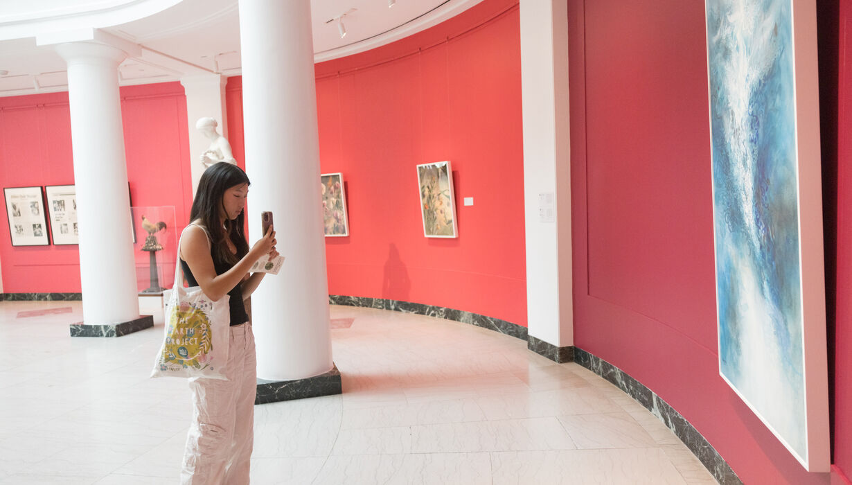 A young female visitor takes a photo of a blue calligraphy painting