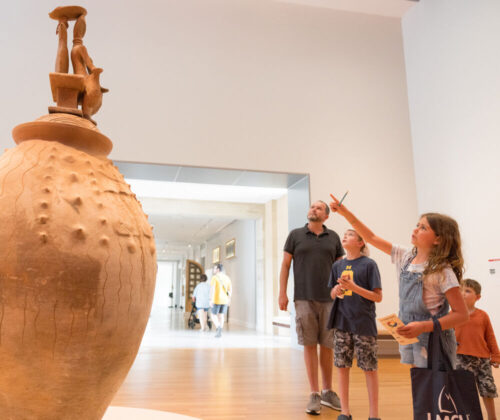 A young family admires a giant pottery piece in the African Art Gallery