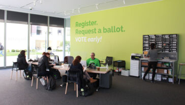A bright green wall reads "Register. Request a ballot. Vote Early Here"