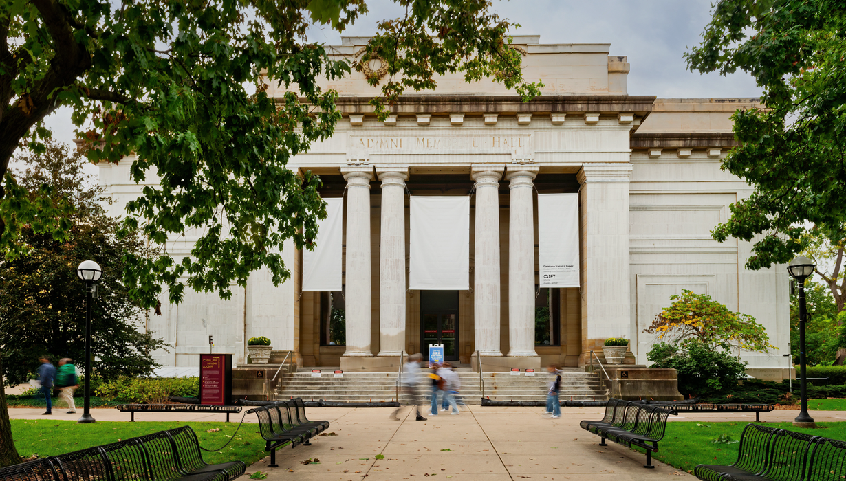 A neoclassical stone building with four columns is seen. The stone has been painted white with a thin porcelain clay slip, making the building stand in stark white contrast against the background