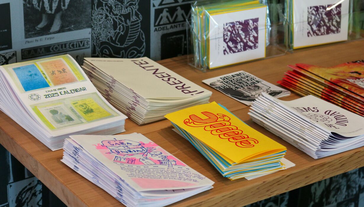 Table displaying an array of colorful printed materials including zines made by UM Stamp Students.