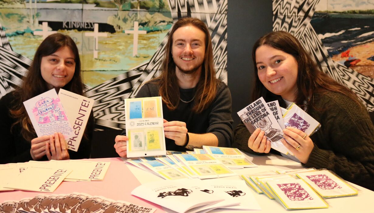 Students gathered outside of the exhibition, sitting at tables with their work displayed.