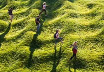 aerial view of four people walking across an undulating field