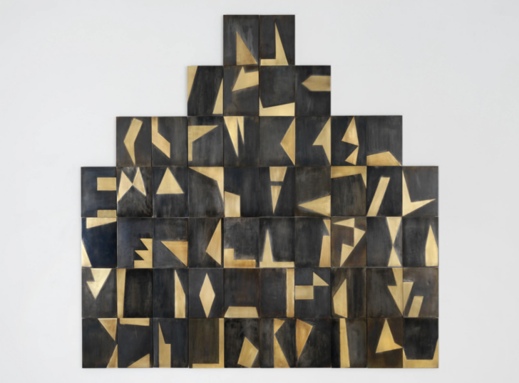 Fifty-four rectangles of identical size, each with a distinct arrangement of brass on black metal, arranged in the shape of a stepped pyramid.