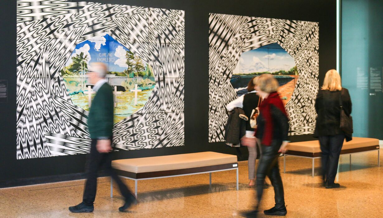 People walking past and looking at Andrea Carlson's Future Cache exhibition.