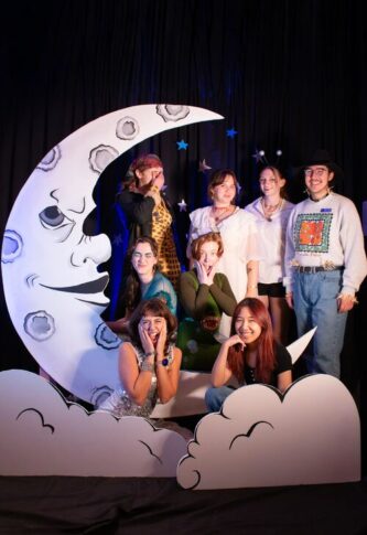 Group of people posing with a crescent moon prop at a themed event