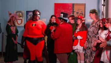 Group of people in costumes, including someone dressed as Mr. Incredible from The Incredibles.