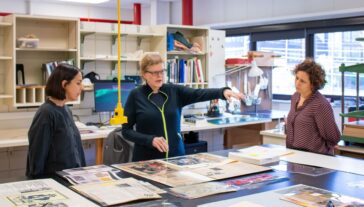 Three individuals discussing archival materials.