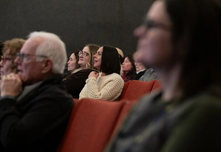 People in audience react to the presentations happening on stage.