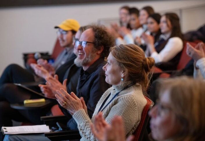 People in audience react to the presentations happening on stage.