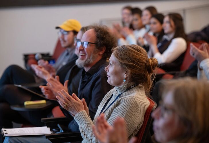 People in audience react to the presentations happening on stage.