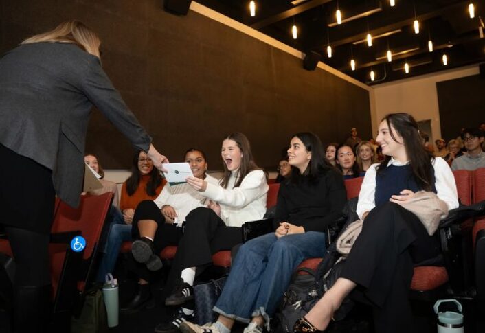 People in audience react to the presentations happening on stage.