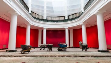 A large atrium room mid construction project - wheelbarrows and torn up tile are littered around.