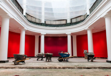 A large atrium room mid construction project - wheelbarrows and torn up tile are littered around.
