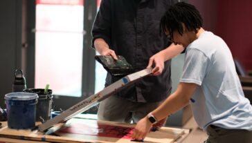 Two people making a silkscreen print.