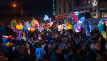 A parade of people at night, all holding paper mache lanterns