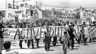 Frame from movie, "Sir! NoSir!" showing people at a protest with many protest banners being shown.