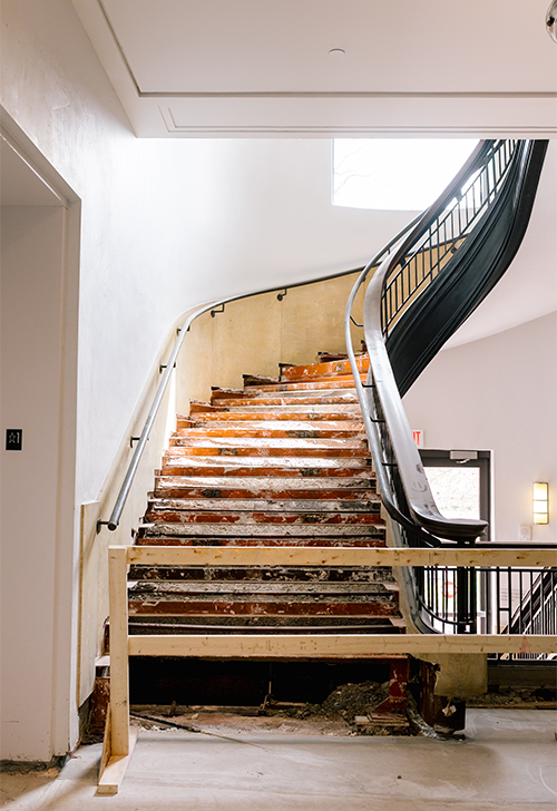 A large staircase is under renovation, exposing the unfinished material underneath.