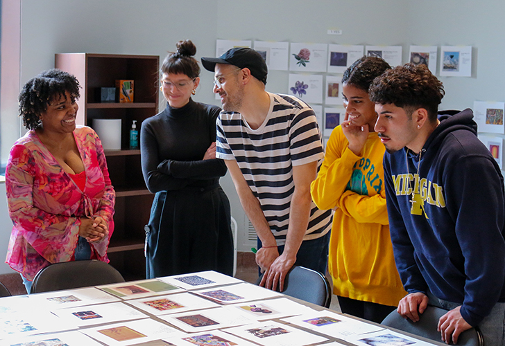 Five individuals collaborate around a table, examining and discussing various photographs and documents.