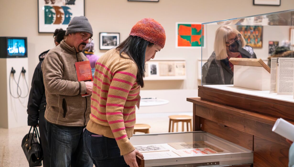 A museum visitor opens a drawer in the American Sampler exhibition