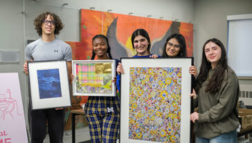 students hold framed artwork and smile