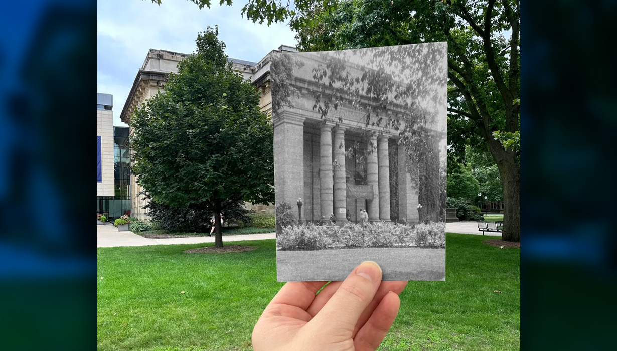 A hand holds an old black and white photo infront of the same spot in present day